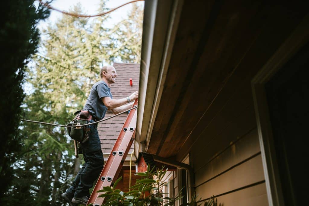 man on ladder smiling climbing up home